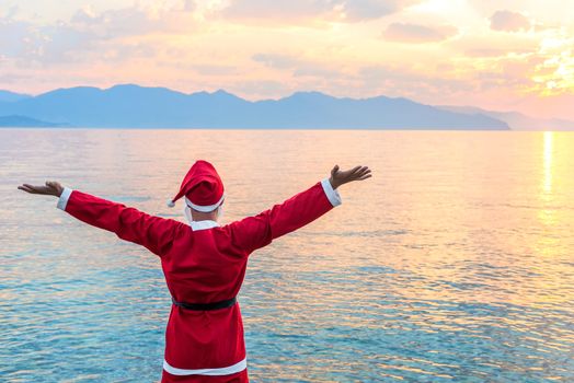 Santa Claus admires the beautiful sunrise over the sea