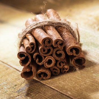 Stack of cinnamon wrapped with a rope over a wooden surface