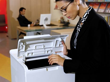 Portrait of young business woman using the photo copy machine 