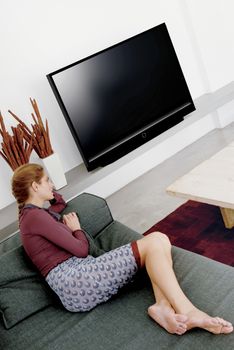 young woman sitting in sofa watching television 