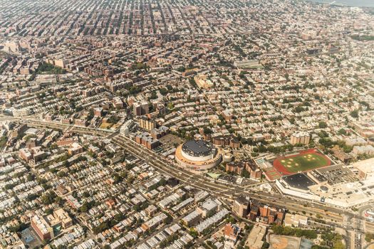 Aerial view of the Borough of Queens, New York, showing densely packed buildings and a multi-lane super highway