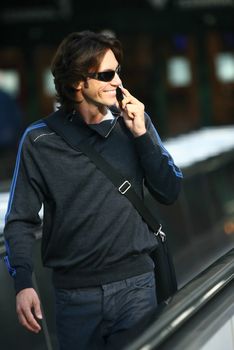 businessman walking down the airport and talking by mobile phone