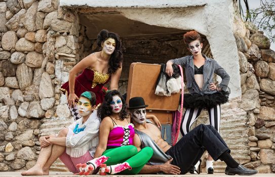 Group of serious bizarre clowns on outdoor stage