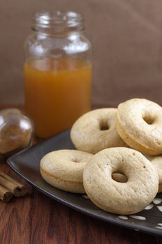 Cider doughnuts on a plate with fresh cinnamon, spices, and cider in the background.