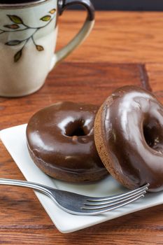 Chocolate frosted doughnuts and coffee on the morning breakfast table.