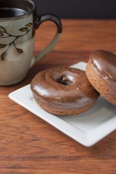 Chocolate frosted doughnuts and coffee on the morning breakfast table.