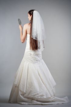 portrait od a bride with long dark hair in wedding dress - isolated on gray