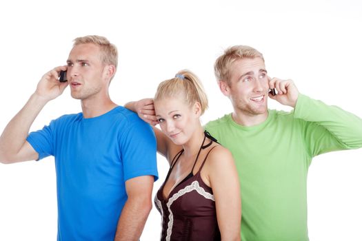 bored young woman standing between two men talking on cell phones- isolated on white