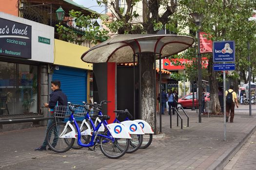 QUITO, ECUADOR - AUGUST 6, 2014: Unidentified man standing at the BiciQuito station of Santa Teresita on Rio Amazonas Avenue on August 6, 2014 in Quito, Ecuador. BiciQuito is a free bike rental service provided by the municipality of Quito.  