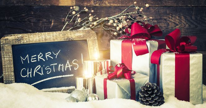 Closeup of Christmas gifts with candles and slate.