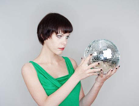 young woman holding a disco ball looking - isolated on gray