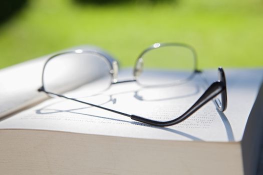 closeup of glasses and an opened book on a table in the garden