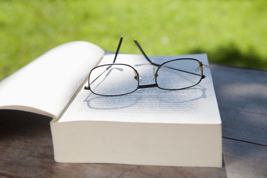 closeup of glasses and an opened book on a table in the garden