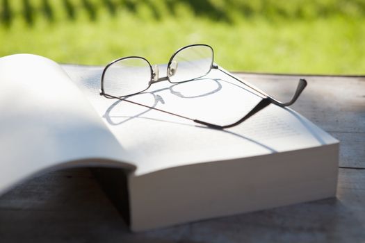 closeup of glasses and an opened book on a table in the garden