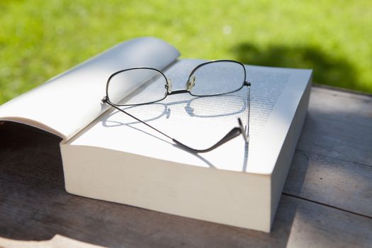 closeup of glasses and an opened book on a table in the garden