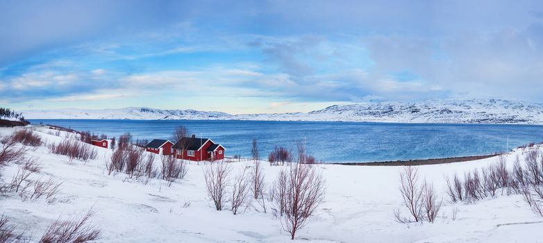 Winter in Norway - mountains with red house and the ocean. Panorama