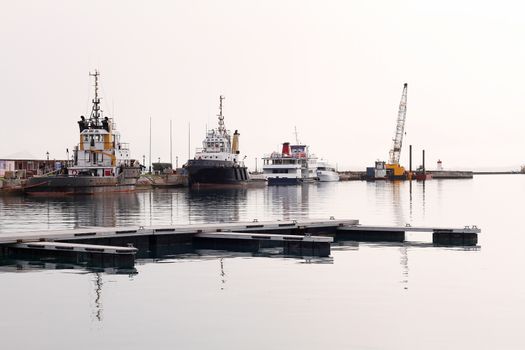 A fleet of pilot boats against a harbour wall, on a hazy day