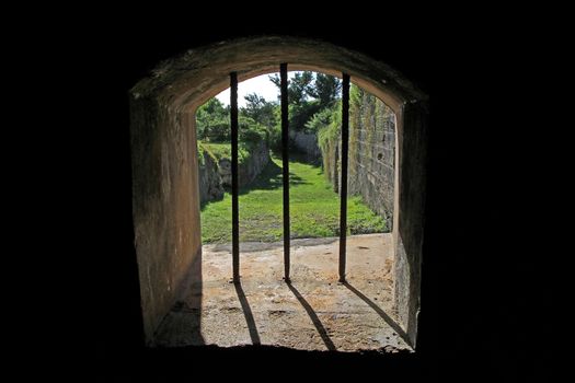 The view through an old jail window, in an historic fort, with bars blocking an escape