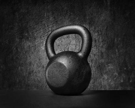 Black and whit image of a rough and tough heavy 30 kg 66 lbs cast iron kettlebell.