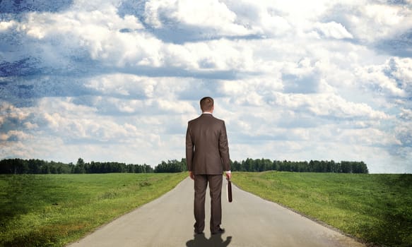 Businessman in suit with briefcase standing on the road. Rear view