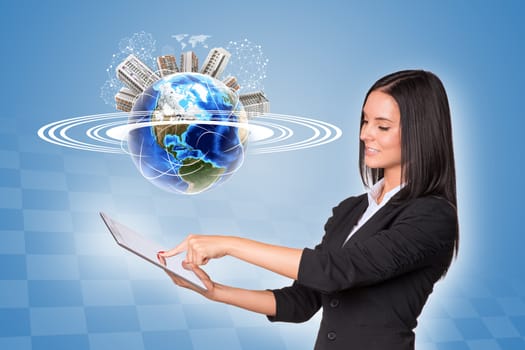 Beautiful businesswoman in suit using tablet. Earth with buildings and wire-frame spheres on blue background. Element of this image furnished by NASA