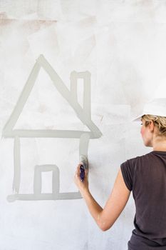 Woman Sketching a House Directly on the Wall with Gray Paint