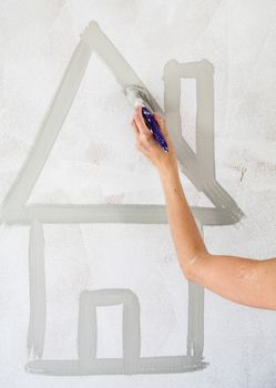 Woman Sketching a House Directly on the Wall with Gray Paint