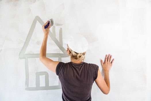 Woman Sketching a House Directly on the Wall with Gray Paint