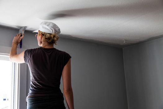Woman Painting the Edges of the Ceiling with Paintbrush