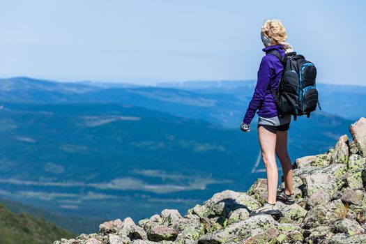 Young Woman with Backpack Looking at the View From the Top of the Hill