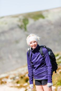 Young Woman Walking on a Rocky Hiking Path and looking at the camera