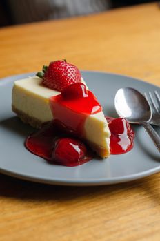 Strawberry Cheesecake with spoon and fork on wooden table