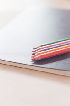 Colorful pencils on black notebook, stock photo