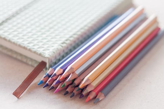 Cluster of colorful pencil crayons with green notebook, stock photo