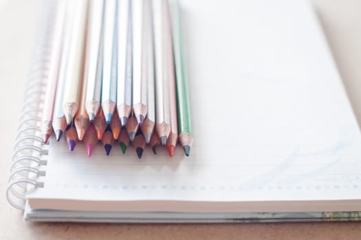 Cluster of colorful pencil crayons on spiral notebook, stock photo