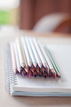 Cluster of colorful pencil crayons with spiral notebook, stock photo