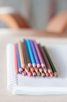 Colorful pencil crayons on spiral notebook, stock photo