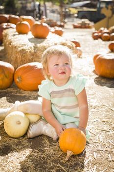 Adorable Baby Girl Holding a Pumpkin in a Rustic Ranch Setting at the Pumpkin Patch.