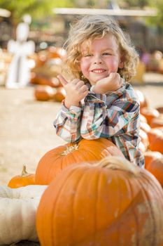 Adorable Little Boy Leaning on Pumpkin Gives a Thumbs Up in a Rustic Ranch Setting at the Pumpkin Patch.