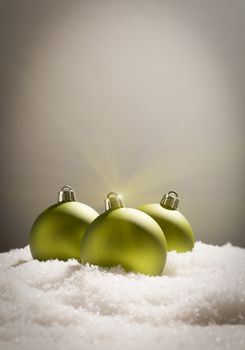 Green Christmas Ornaments on Snow Flakes Over a Grey Background