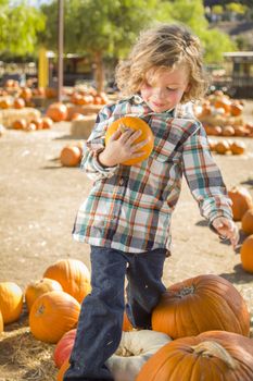 Adorable Little Boy Sitting and Holding His Pumpkin in a Rustic Ranch Setting at the Pumpkin Patch.