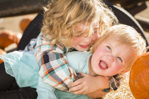 Sweet Little Boy Plays with His Baby Sister in a Rustic Ranch Setting at the Pumpkin Patch.