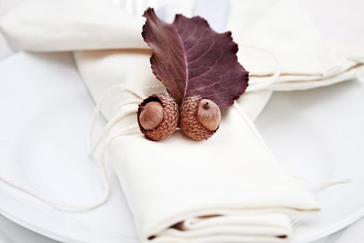 Rustic table decorated with leaves and acorns, ready for a Thanksgiving meal.