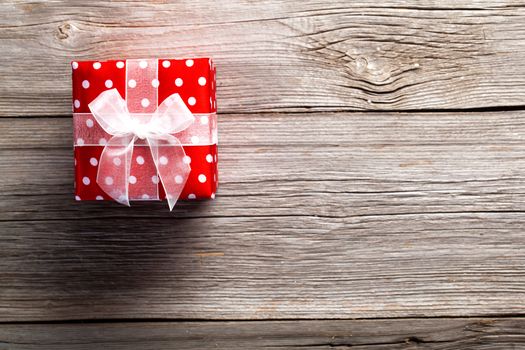red gift box, polka dots, on wood background