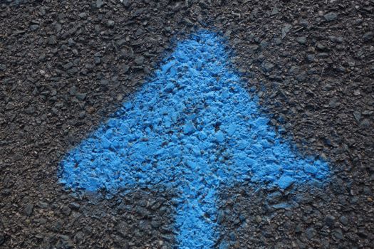 Arrow in blue paint on tarmac pointing upwards