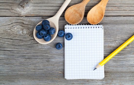 top view of recipe book with fresh Blueberries ingredients on wooden table