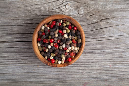 Colored Pepper in the wooden bowl, on wooden board