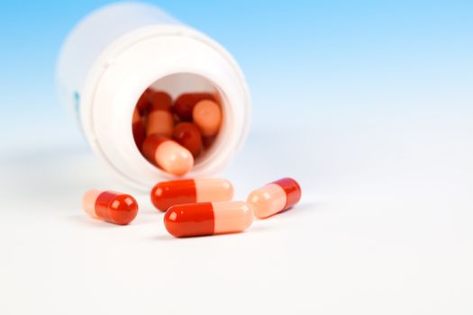 Pills spilling out of pill bottle isolated on blue (with sample text)