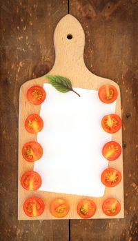 blank sheet of paper and half cherry tomatoes on a cutting board
