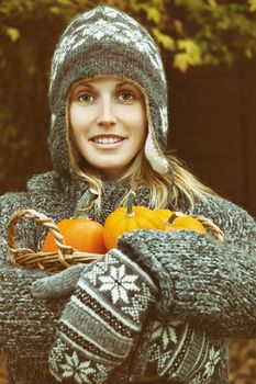 Young woman holding a basket of small pumpkins 